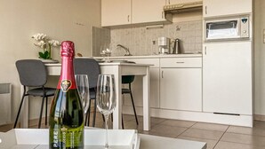 A modern kitchen with white cabinets, a microwave, and a coffee maker. There is a table with a bottle of wine and two glasses. - Pet friendly apartment in Oostende (Oostende)