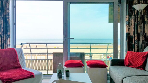 A room with a view of the beach, a sofa, a chair, and a table with a plant. - Pet friendly apartment in Oostende (Oostende)