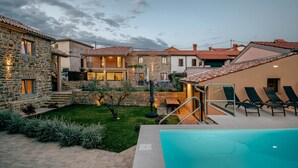 A residential property with a swimming pool, outdoor seating, and a stone facade.