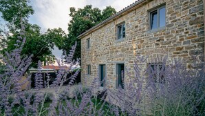 A stone building with a garden featuring purple flowers.