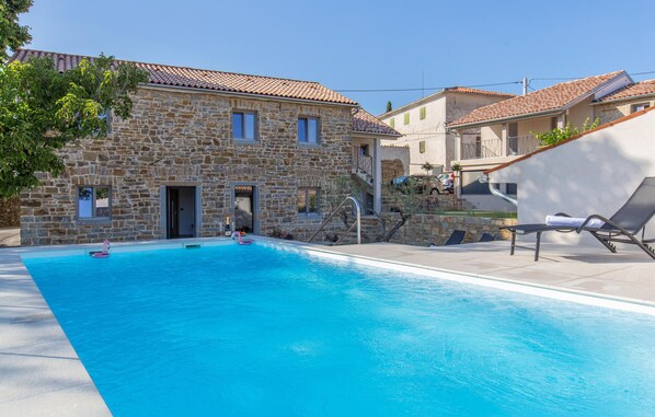 A stone building with a swimming pool, a lounge area, and a car parked nearby. - Awesome home in Skofije (Skofije)