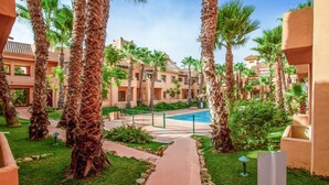 Un patio de hotel con palmeras, una piscina y un camino que lleva a la piscina.