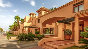 Un hotel de estilo arquitectónico moderno, con un patio central con palmeras y cielo despejado.