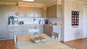 A modern kitchen with wooden cabinets, a built-in oven, and a dining table with a placemat.