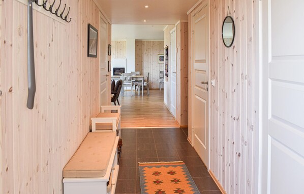 A hallway with wooden walls, a bench, a rug, and a dining area in the background. - Nice home in Sjusjøen with kitchen (Sjusjøen)