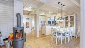 A modern kitchen with white cabinets, a central island, and a wood-burning stove.