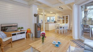A cozy cabin interior with a wooden interior, a dining area, a kitchen, and a TV on the left.