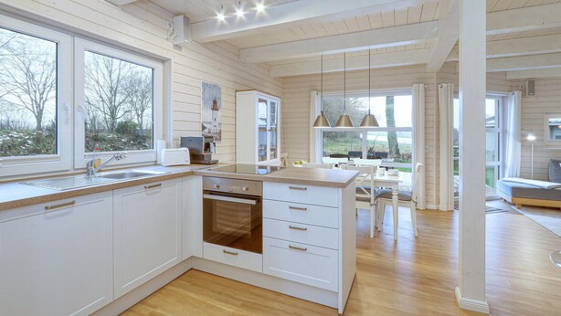 A modern kitchen with wooden paneling, a large island, and ample natural light.