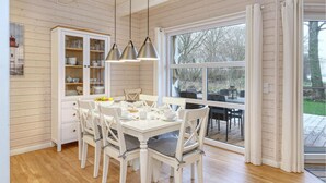 A kitchen with a large window, wooden cabinets, and a dining table set for four.
