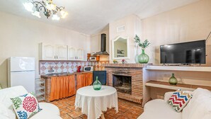 Une cuisine compacte avec un dosseret carrelé, un four encastré et un téléviseur à écran plat placé au-dessus d’une cheminée.