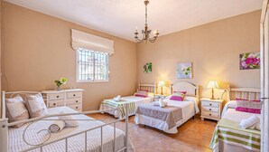 Une chambre d’hôtel avec deux lits simples, un petit bureau, une chaise, une fenêtre donnant sur un beau paysage et un lustre.