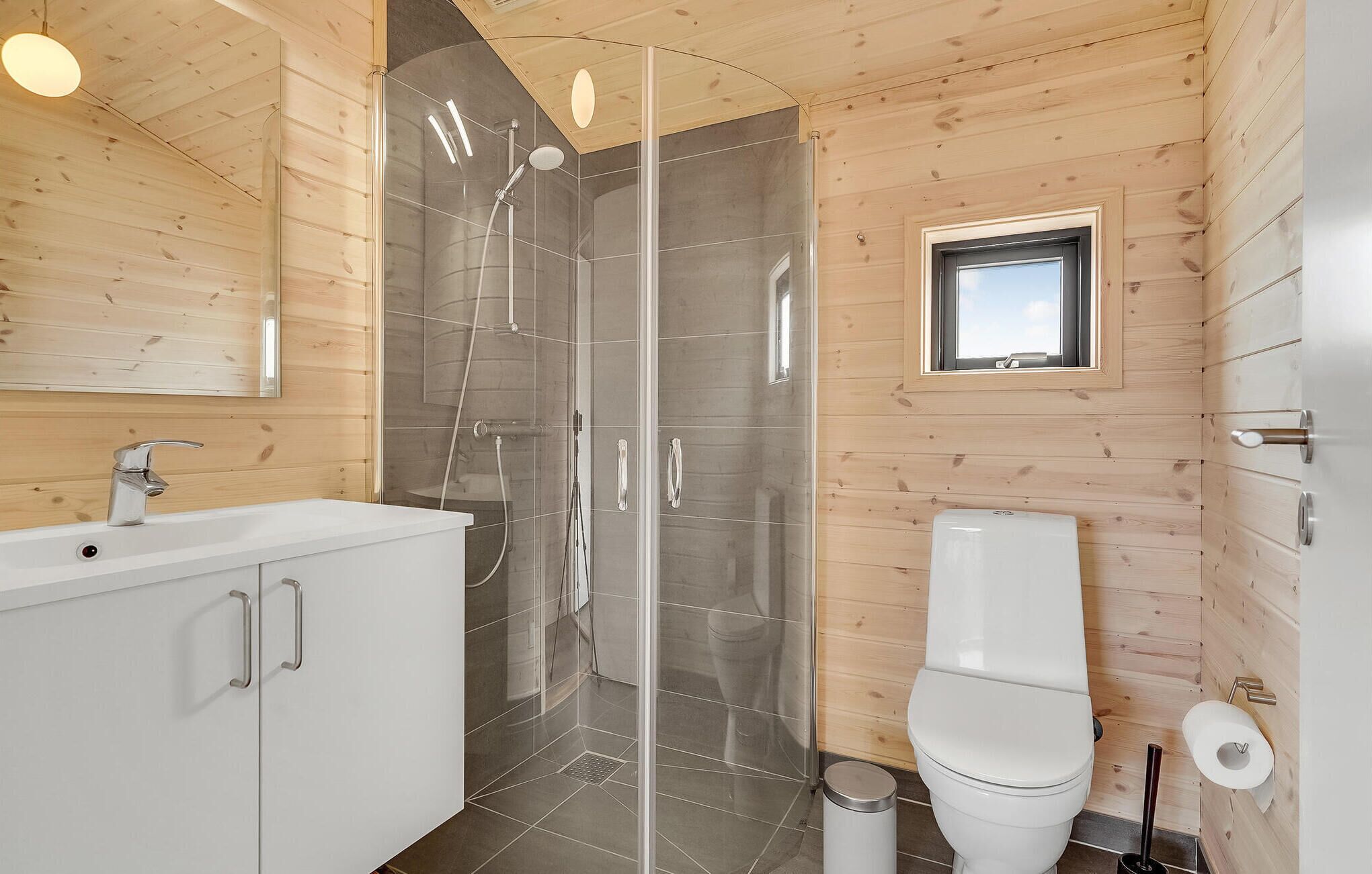 Une salle de bain moderne avec une douche à parois de verre, un lavabo blanc et des toilettes.