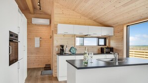 A modern kitchen with wooden walls, white cabinets, and a large window offering a view of the countryside. - Stunning home in Storvorde with WiFi (Storvorde)