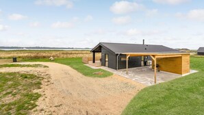 A modern house with a covered porch, a dirt path leading to it, and a grassy field in the background. - Stunning home in Storvorde with WiFi (Storvorde)