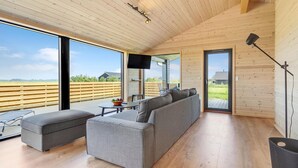 A modern interior with a large gray sofa, a small table with a bowl of fruit, and a TV mounted on the wall. - Stunning home in Storvorde with WiFi (Storvorde)