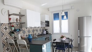 Una cucina moderna con isola centrale, mobili bianchi e frigorifero in acciaio inossidabile.