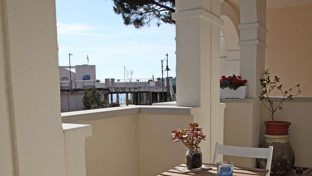 Un balcone con tavolo e sedie, piante in vaso e vista sulla città.