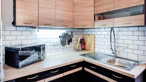 Eine moderne Küche mit Holzschränken, einer Edelstahl-Spüle und einer eingebauten Mikrowelle.