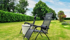 Ein Garten mit einem schwarzen Gartenstuhl und einem weißen Tisch.