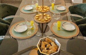 A dining table set with placemats, plates, glasses, and candles.