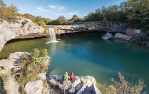 A natural landscape with a waterfall, rocky terrain, and a clear view of the water.