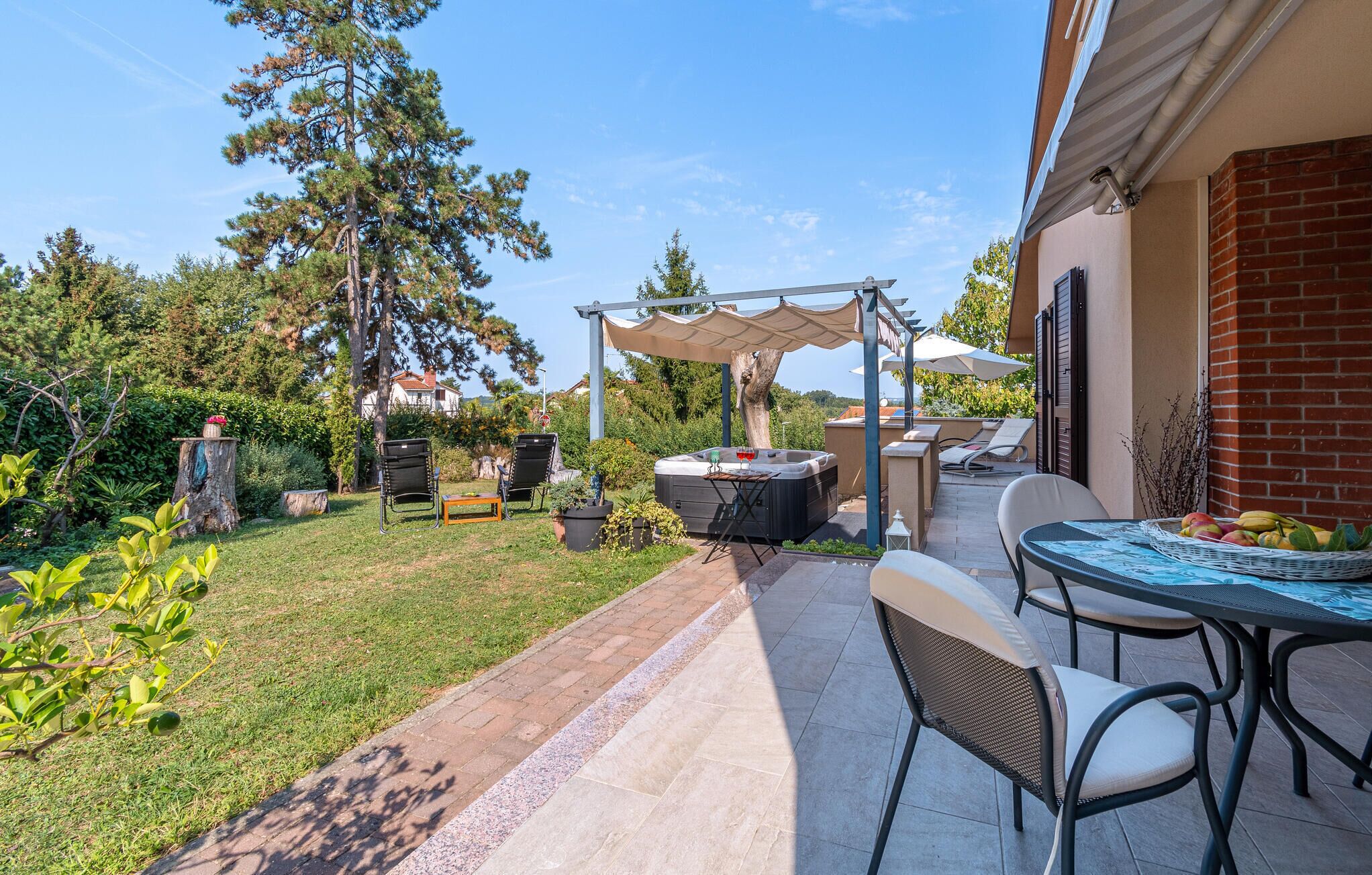 A patio area with outdoor seating, a hot tub, and a pergola providing shade.