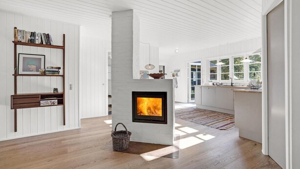 Een moderne keuken met een centraal gelegen open haard, houten vloeren en witte kasten.