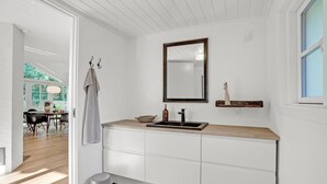 Een badkamer met een houten wastafelmeubel, een spiegel, een handdoekhouder en een klein plankje met een decoratief object.
