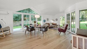 Een ruime kamer met een grote eettafel, meerdere stoelen en een gezellige zithoek.