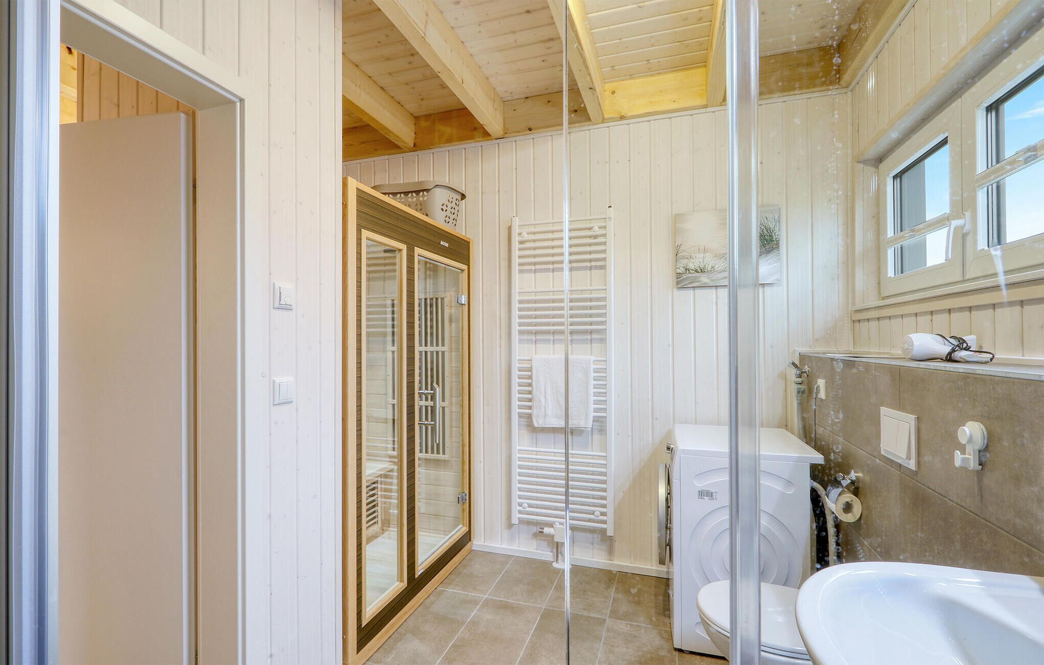 Ein Badezimmer mit Duschkabine, Toilette, Waschbecken und Fenster.
