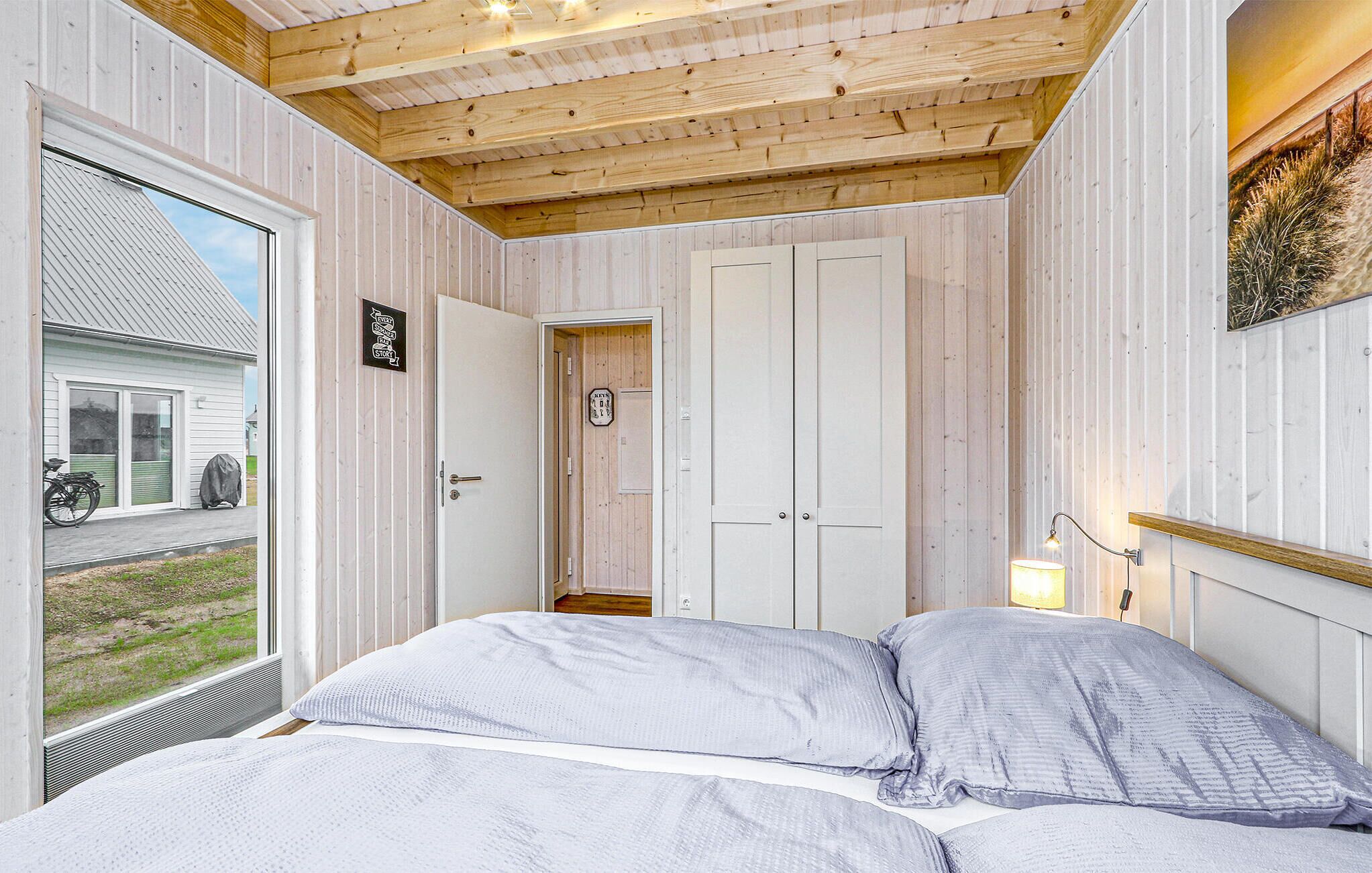 Une chambre à coucher avec un lit, un plafond en bois et une vue sur l’extérieur.
