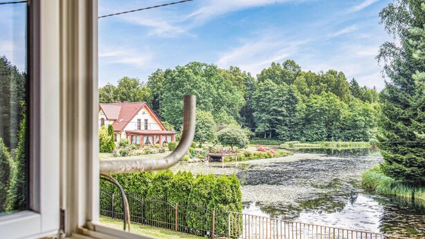 Uitzicht op een rivier met een huis, een houten steiger en een metalen hek.