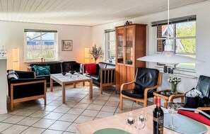 Una sala acogedora con un sofá, un aparador de madera, una mesa de comedor y vistas al exterior.