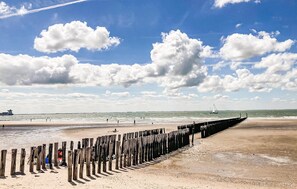 A beach with a wooden jetty, calm sea, and a sailboat in the distance. - 1 bedroom cozy home in Zoutelande (Zoutelande)
