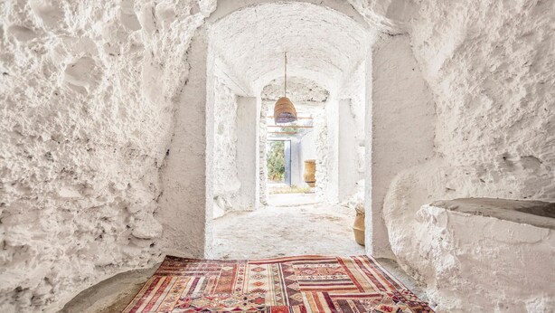 A narrow, arched passageway with a patterned rug on the floor, leading to a doorway with a hanging light fixture. - Beautiful home in Nigüelas (Nigüelas)