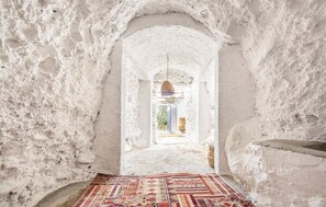A narrow, arched passageway with a patterned rug on the floor, leading to a doorway with a hanging light fixture. - Beautiful home in Nigüelas (Nigüelas)