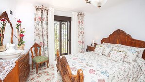 A bedroom with a wooden bed, floral bedding, a wooden dresser, a chair, and a mirror. - 2 bedroom cozy apartment in Monterio (Monterio)