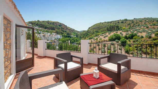 A balcony with wicker furniture and a view of a hillside village. - 2 bedroom cozy apartment in Monterio (Monterio)