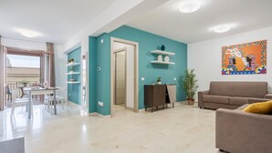 En moderne stue med en teal farvet væg, en brun sofa og et spiseområde med bord og stole.