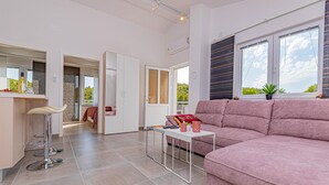 Ein modernes Wohnzimmer mit einem rosafarbenen Sofa, einem kleinen weißen Tisch und einer Bar mit einem Hocker.