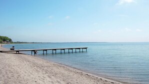 A beach with a wooden pier extending into calm waters, sandy shore, and a clear sky. - Stunning home in Haderslev with sauna (Haderslev)