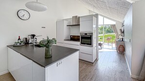 A modern kitchen with a central island, a built-in oven, and a dining area with a view of the garden. - Stunning home in Haderslev with sauna (Haderslev)