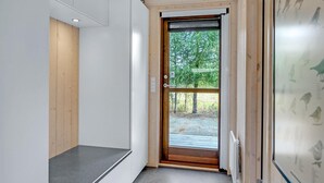 Un interior moderno con una puerta de madera que da a un área exterior, un banco y una pared con ilustraciones de aves.