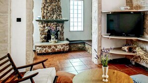 A cozy living room with a stone fireplace, a television, and a comfortable seating area. - Awesome home in Novo Selo (Novo Selo)