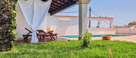 A covered outdoor seating area with a pool, a pergola, and a view of the sea.