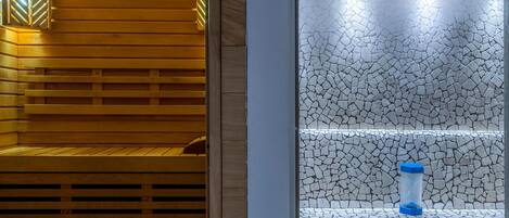 A sauna with wooden benches and a stone wall.