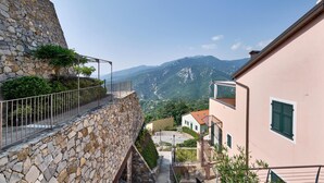 A stone-walled building with a balcony overlooking a mountainous landscape.