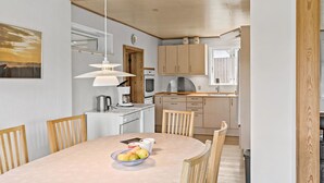 Eine moderne Küche mit Holzausstattung, einem Esstisch mit Stühlen und einer Hängelampe.