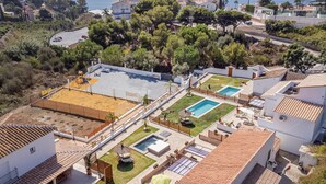 Zona residencial con una piscina grande, cancha de tenis y un pequeño jardín.