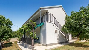 Un bâtiment moderne à l’extérieur blanc, doté d’un balcon avec une rambarde en métal et d’un escalier menant à l’entrée.